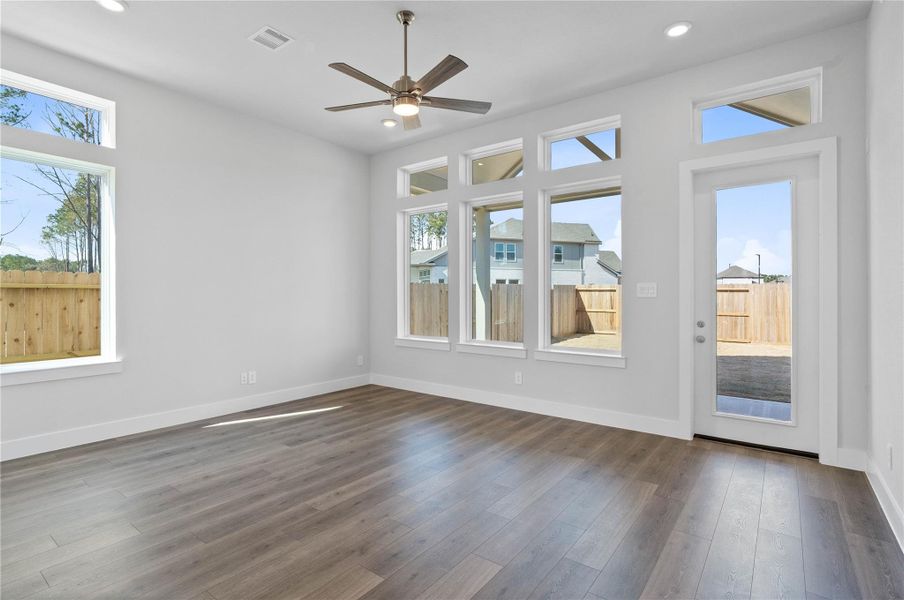 Soaring, tall windows frame the living space, bathing the room in natural light and highlighting the architectural volume of the space. A convenient back door provides direct and easy access to a comfortable covered patio, effortlessly extending your living space outdoors for year-round enjoyment and entertaining.