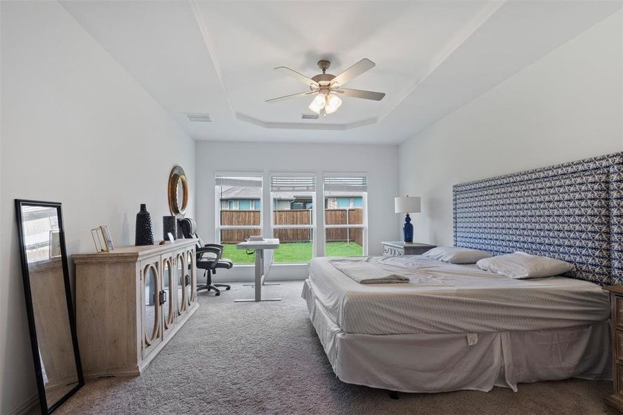 Bedroom with a tray ceiling, carpet flooring, and a ceiling fan