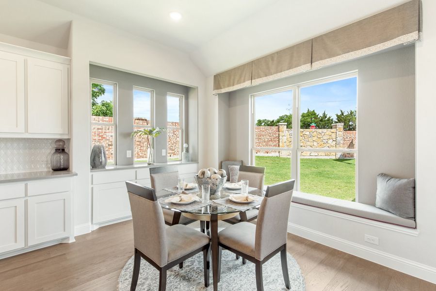 Breakfast nook with round glass table, four gray chairs, window seat, and large windows overlooking backyard Breakfast nook with round glass table, four gray chairs, window seat, and large windows overlooking backyard