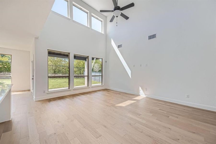 Vaulted ceilings with a ceiling fan, light wood-finish flooring, and multiple large windows with exterior green space Vaulted ceilings with a ceiling fan, light wood-finish flooring, and multiple large windows with exterior green space
