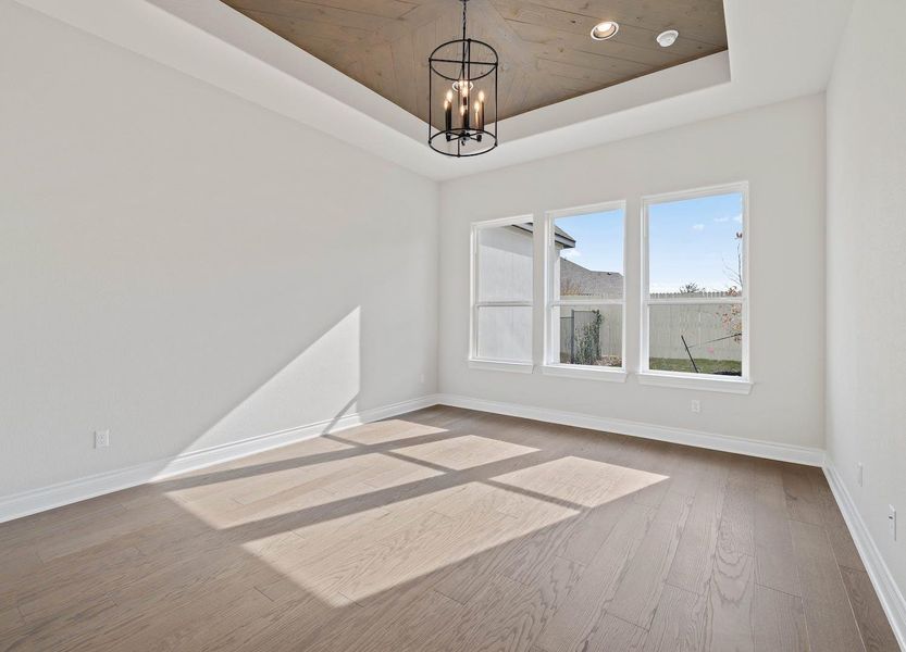 Unfurnished dining area featuring baseboards, a raised ceiling, a notable chandelier, and wood finished floors Unfurnished dining area featuring baseboards, a raised ceiling, a notable chandelier, and wood finished floors