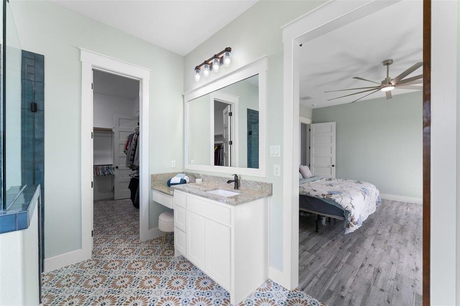Bathroom featuring a single vanity with granite countertop, an integrated sink, and white cabinetry