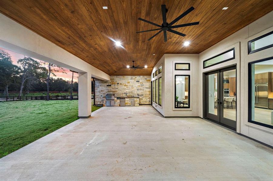 Huge outdoor living/dining/kitchen with pine ceiling as seen from the stone fireplace.