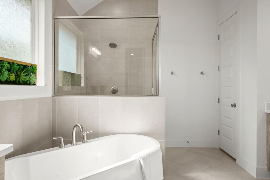 Luxurious soaking tub and tiled shower with contemporary fixtures create a spa-like retreat.