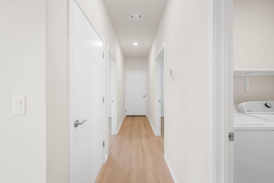 A well-lit hallway with natural wood flooring leads to various rooms, offering a clear and inviting passage. A well-lit hallway with natural wood flooring leads to various rooms, offering a clear and inviting passage.