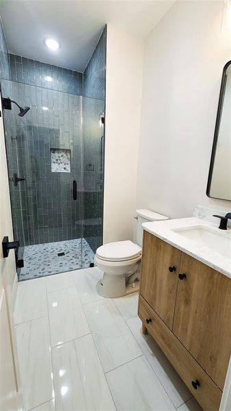 Bathroom with vanity, toilet, and a shower with shower door