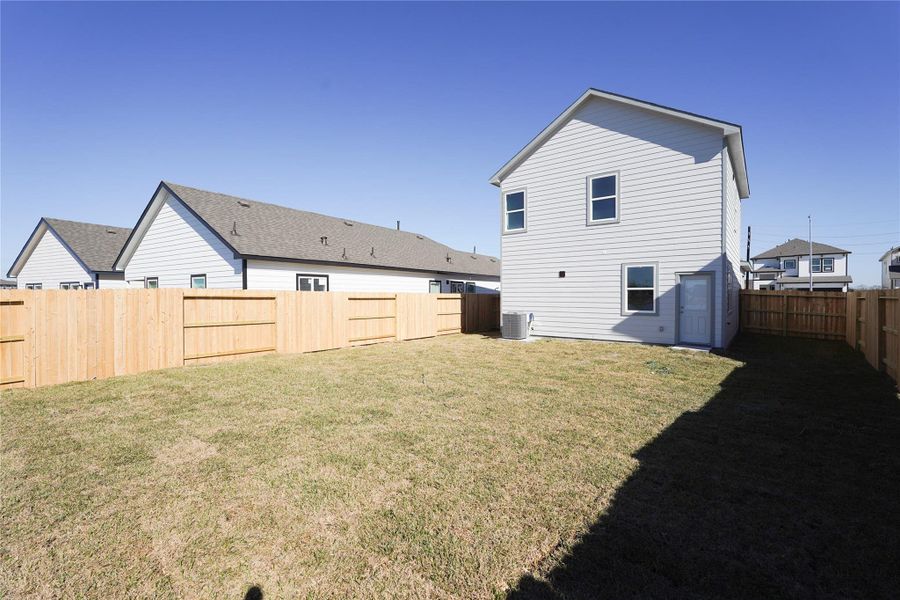 Spacious fenced backyard with a well-maintained lawn, ideal for outdoor activities. The house features a modern exterior with two stories, offering plenty of natural light.
