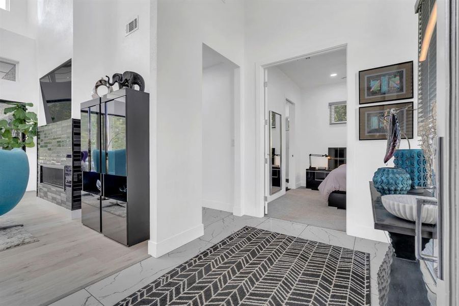 Hallway with light marble finish flooring, a towering ceiling, and recessed lighting