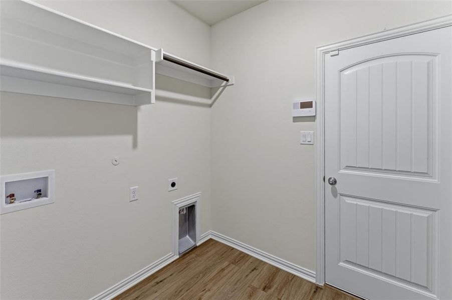 Utility space featuring wood-finish flooring, white baseboards, and light neutral wall paint