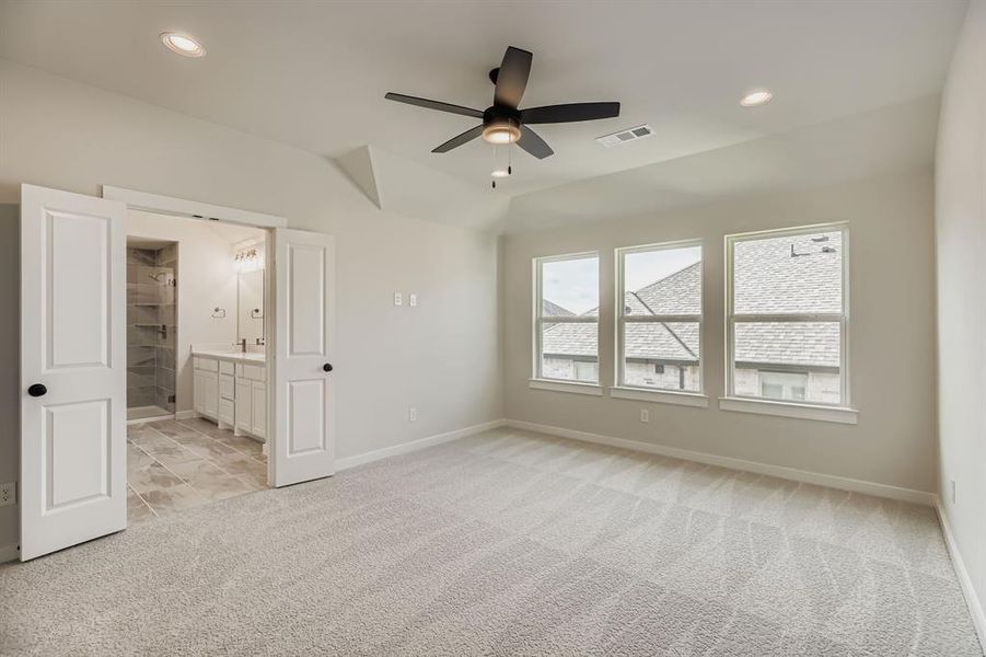 Unfurnished bedroom featuring light carpet, vaulted ceiling, recessed lighting, connected bathroom, and a ceiling fan