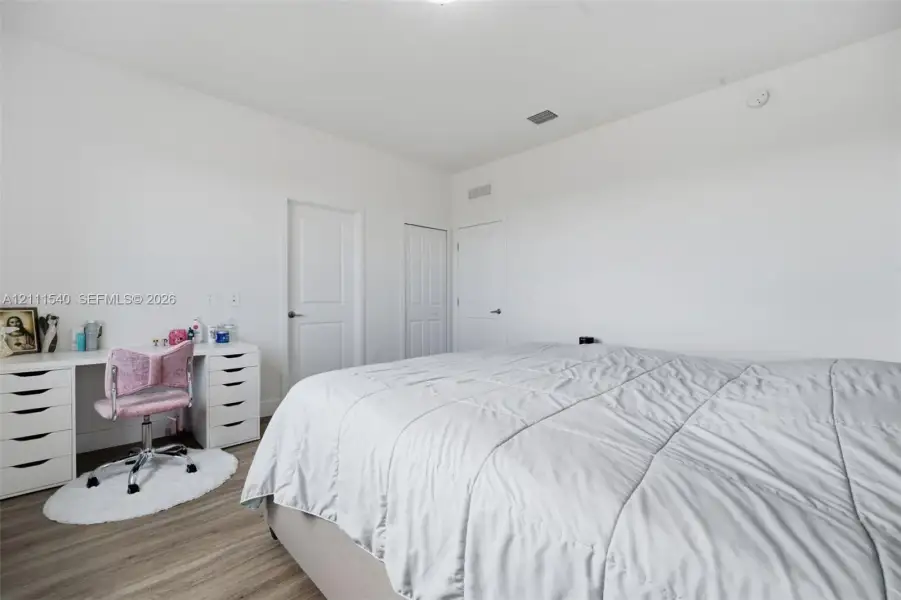 Neutral-toned interior featuring wood-finish flooring, crisp white walls, and multiple solid-core panel doors