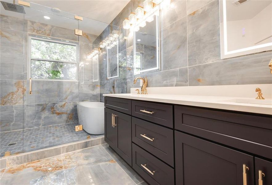 Bathroom featuring vanity, independent shower and bath, and tile walls