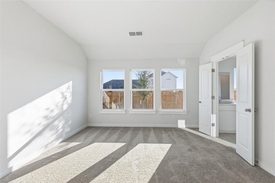 Carpeted spare room featuring lofted ceiling and baseboards