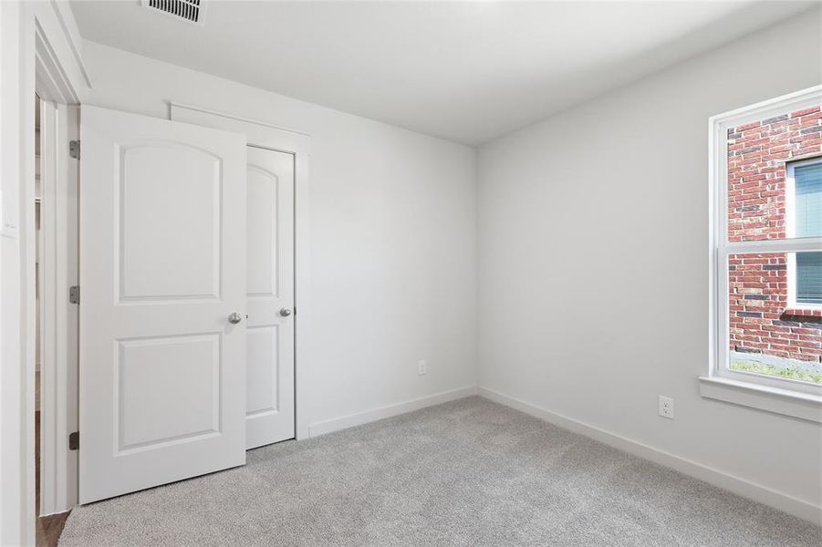 Unfurnished bedroom with light carpet and baseboards