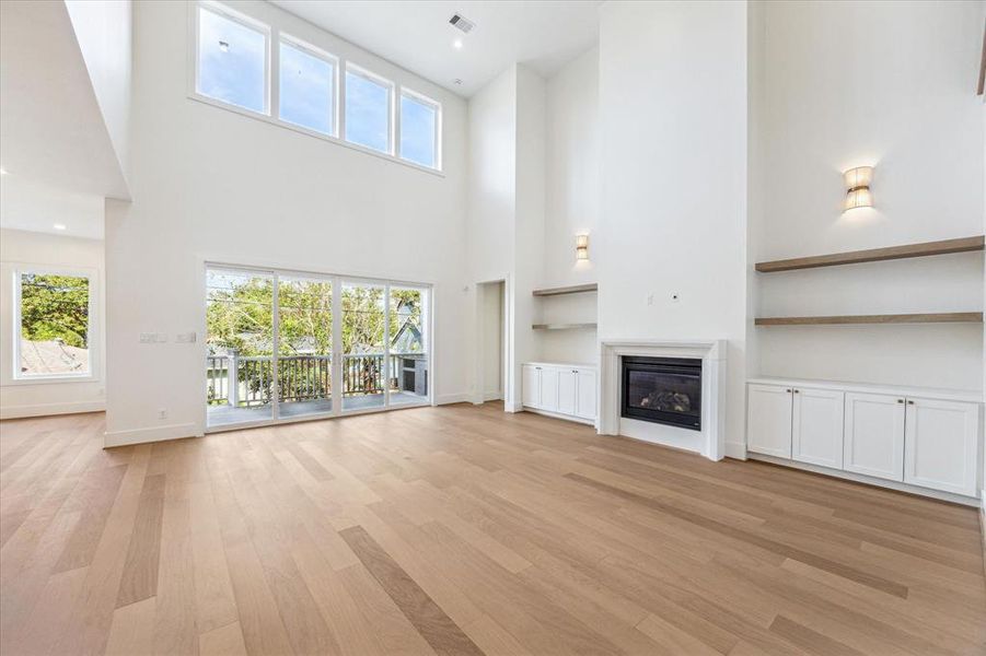 Just beyond the foyer, a spacious family room awaits, with a continuation of the soaring 20-foot ceilings, large picture windows, sliding glass doors, built-in shelving and cabinetry flanking the fireplace, and wide plank wood floors. The open-concept design flows seamlessly into the kitchen and dining area, while an outdoor kitchen on the deck invites easy entertaining. Photos as of 11/5/2024