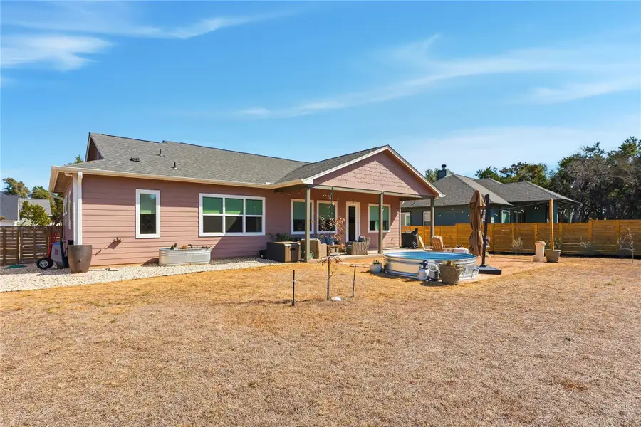 Back of house with a fenced backyard, a patio area, and a jacuzzi