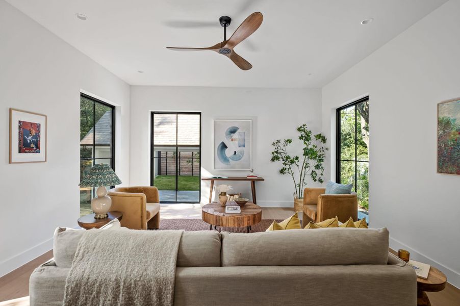 Bright, open living area featuring wide-plank wood flooring and a modern ceiling fan.