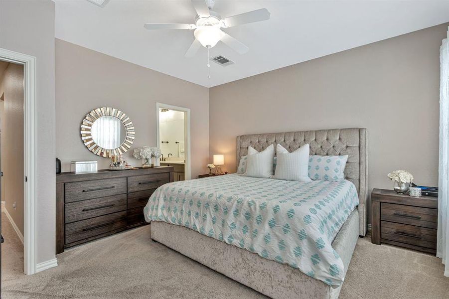 Bedroom featuring ceiling fan, light carpet, and ensuite bathroom