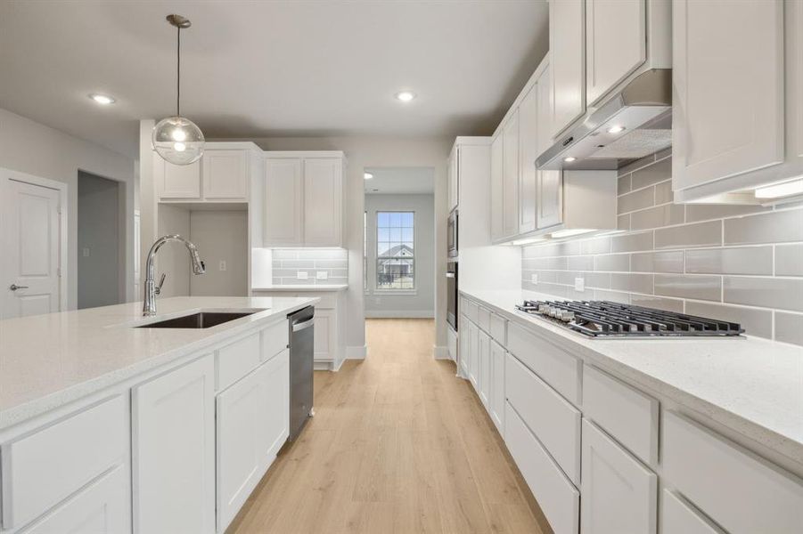 Kitchen featuring white cabinetry, light stone countertops, and sink