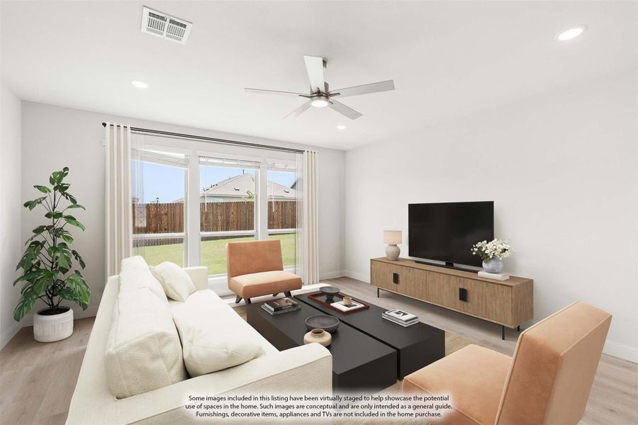 Living room with white sofa, ceiling fan, wood-tone media console, and large windows with backyard view