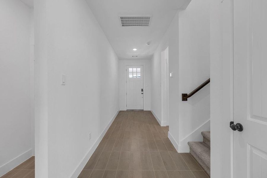 The natural light and high ceilings in this entry hallway make this space a welcoming path to the stairway and secondary bedroom.