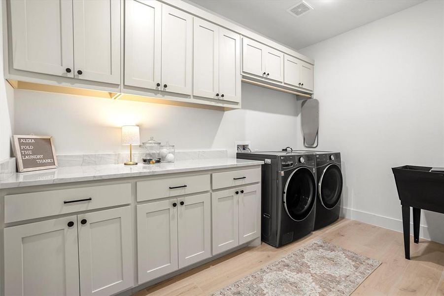 Laundry room with cabinets, separate washer and dryer, and light hardwood / wood-style flooring