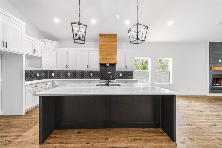 Kitchen featuring white cabinetry, tasteful backsplash, hanging light fixtures, light stone countertops, and recessed lighting