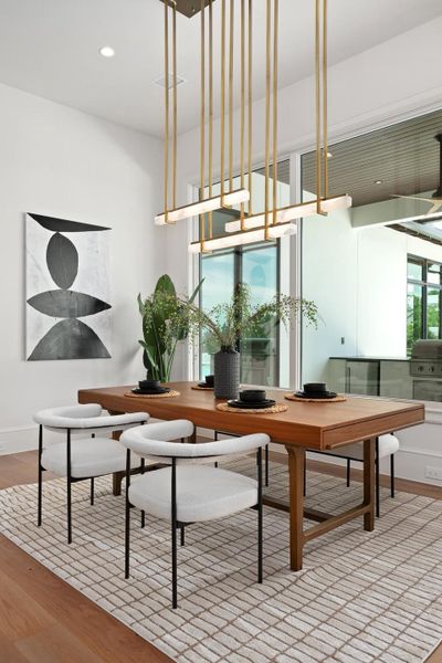 A striking linear chandelier illuminates this dining space with hardwood floors and ample natural light.