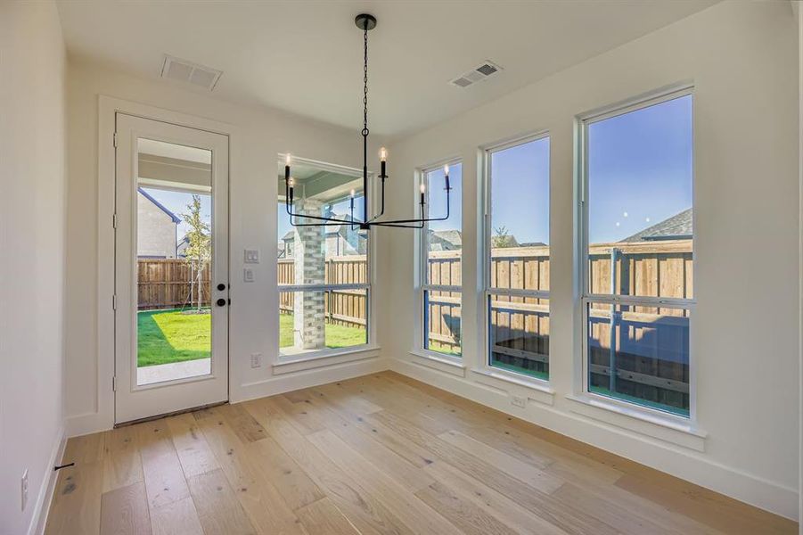 Unfurnished dining area featuring a chandelier and light wood-style floors Unfurnished dining area featuring a chandelier and light wood-style floors