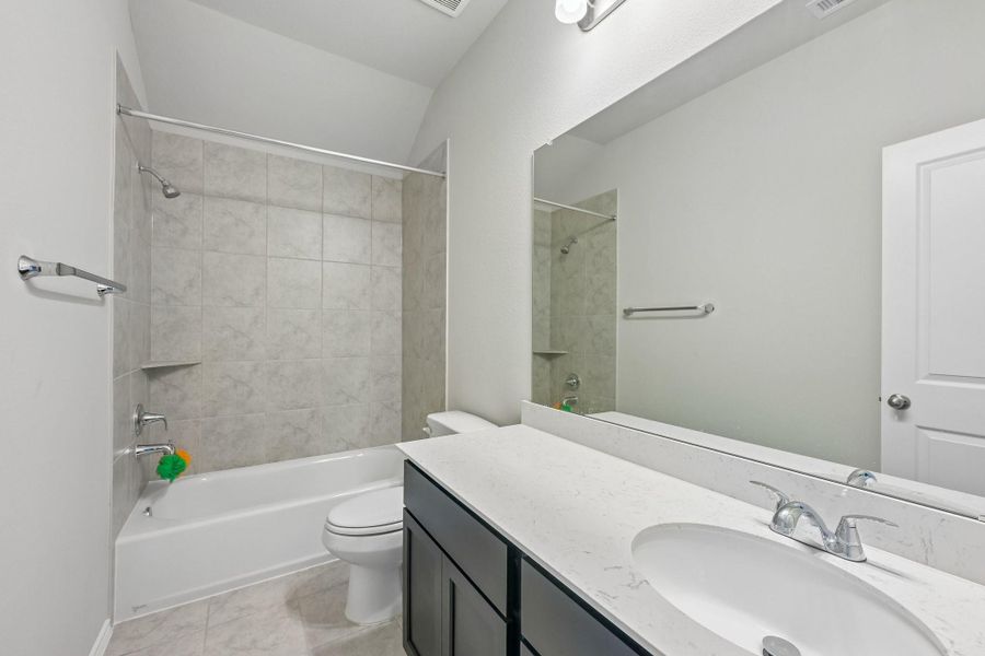 Modern bathroom featuring a sleek vanity with a large mirror, complemented by a tiled shower and bathtub.