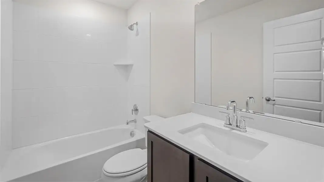 Bathroom featuring a tub/shower combination with white subway tile surround, chrome fixtures, and a corner shelf