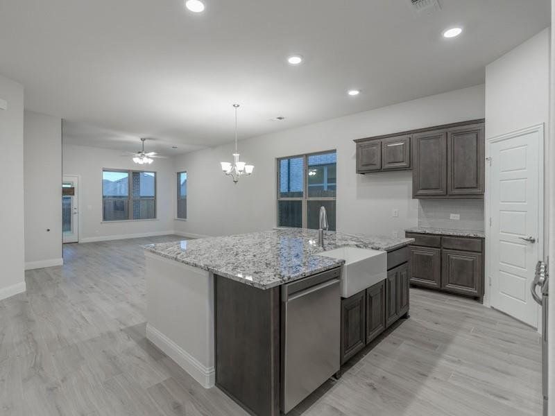 Kitchen with dishwasher, sink, hanging light fixtures, a kitchen island with sink, and dark brown cabinetry