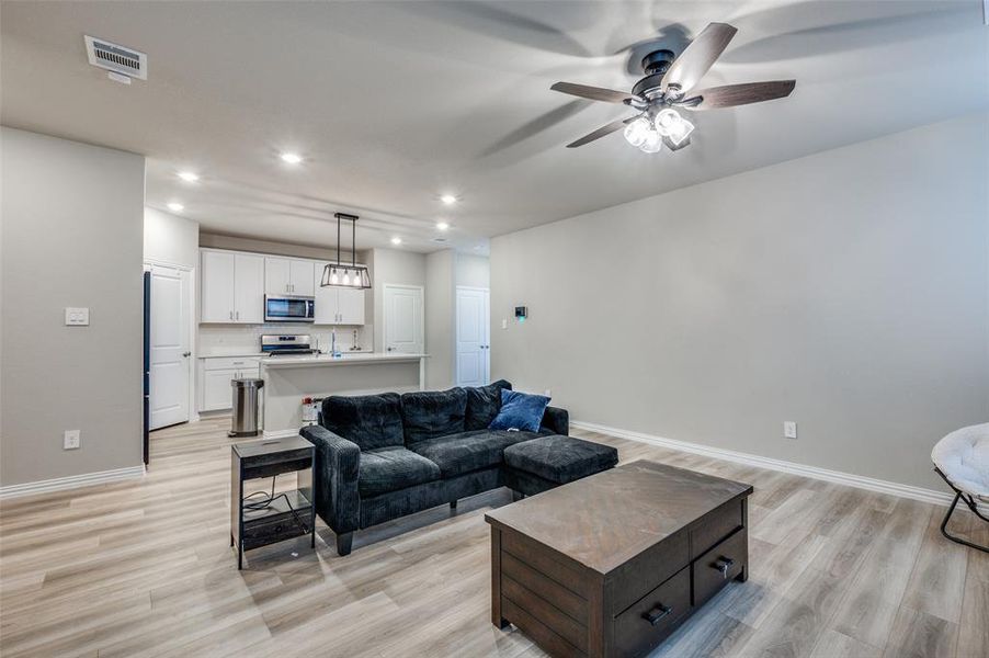Living room with recessed lighting, light wood finished floors, and a ceiling fan
