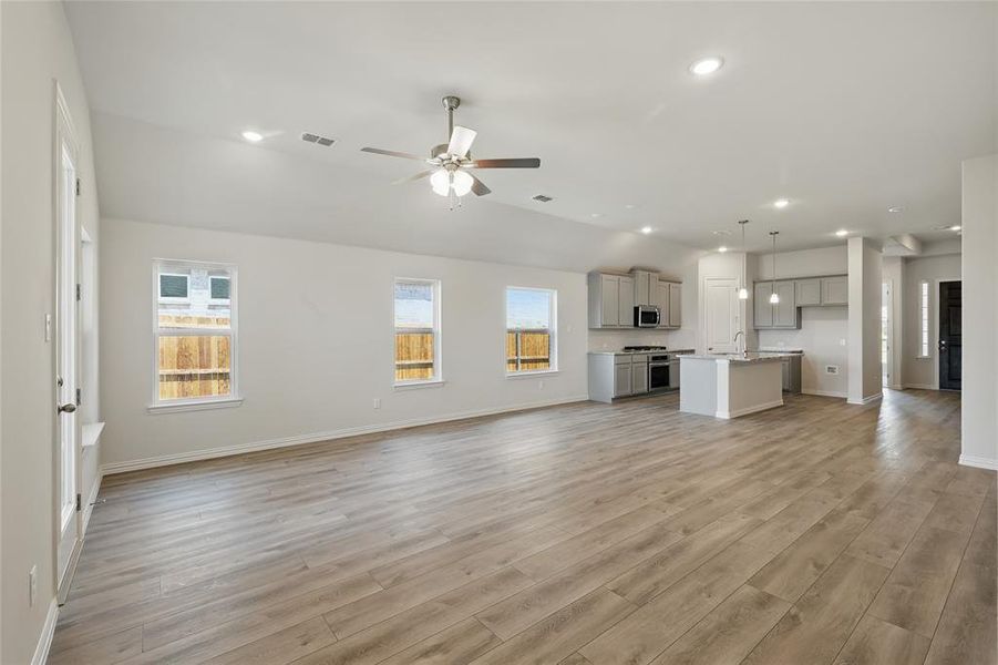 Unfurnished living room with a ceiling fan, plenty of natural light, light wood-style flooring, recessed lighting, and vaulted ceiling Unfurnished living room with a ceiling fan, plenty of natural light, light wood-style flooring, recessed lighting, and vaulted ceiling