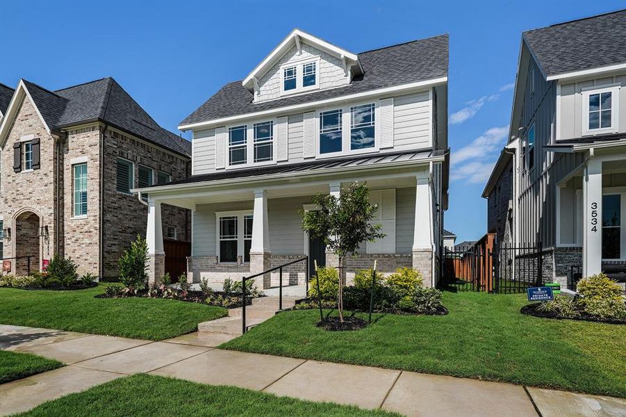 Traditional style home with brick siding, roof with shingles, covered porch, and a standing seam roof