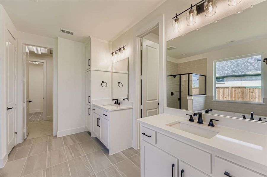 Full bath with a stall shower, two vanities, and light tile patterned floors
