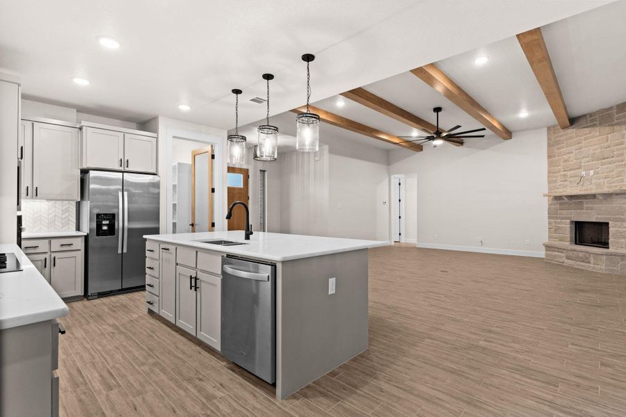 Kitchen featuring hanging light fixtures, stainless steel appliances, a kitchen island with sink, open floor plan, and ceiling fan Kitchen featuring hanging light fixtures, stainless steel appliances, a kitchen island with sink, open floor plan, and ceiling fan