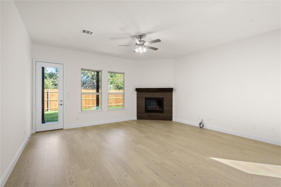 Unfurnished living room featuring light wood-type flooring, a brick fireplace, and a ceiling fan