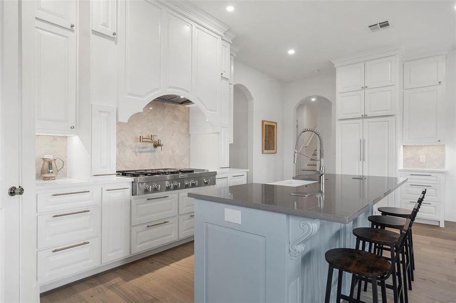 Kitchen featuring tasteful backsplash, dark stone counters, white cabinetry, recessed lighting, and an island with sink Kitchen featuring tasteful backsplash, dark stone counters, white cabinetry, recessed lighting, and an island with sink