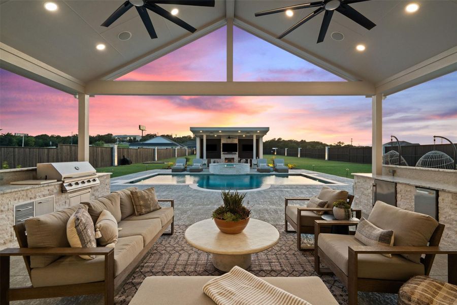 An inviting outdoor living area features an integrated kitchen, sparkling pool, and open-air pavilion, all set against a vibrant sunset. An inviting outdoor living area features an integrated kitchen, sparkling pool, and open-air pavilion, all set against a vibrant sunset.