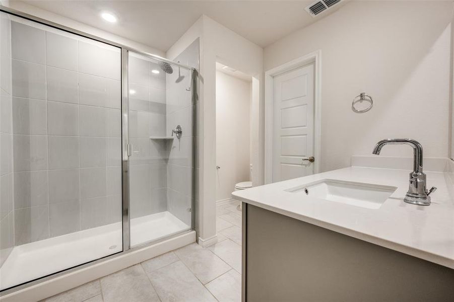 Bathroom with vanity, light tile patterned floors, and a stall shower