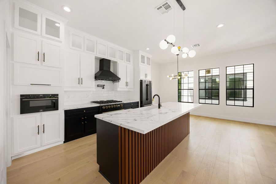 A thoughtful designed kitchen featuring quartz countertops, premium appliances, a touch activated  microwave drawer, pop-up power outlets, designer lighting , and stylish toe-kick lighting. Natural light brightens the space, whie the custom breakfast bar creates an inviting area for casual dining and enertaining.