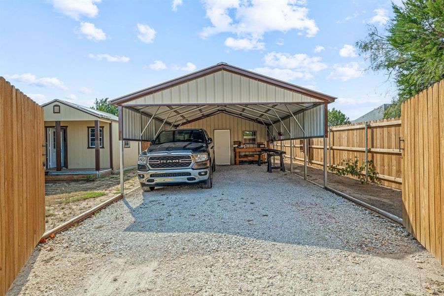 View of car parking featuring a detached carport and gravel driveway