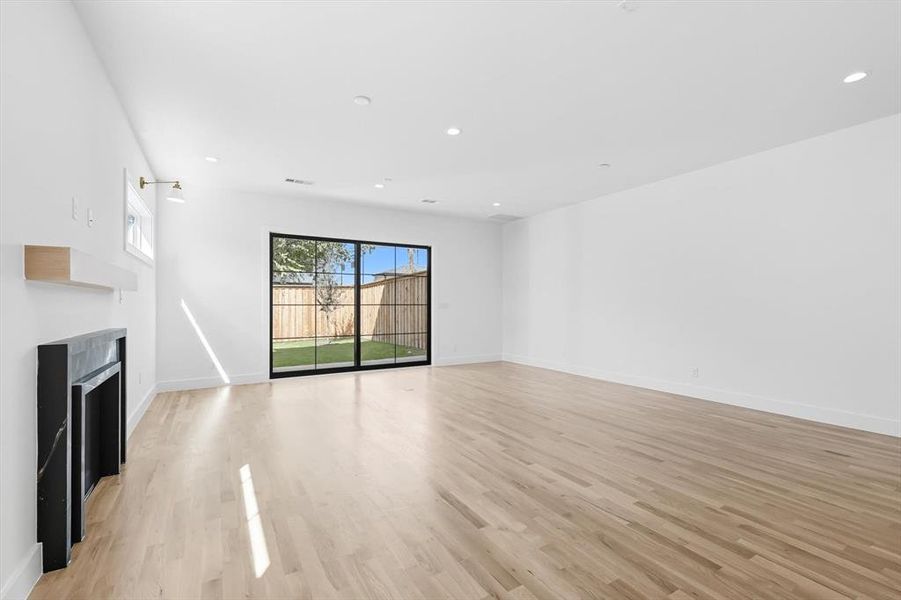 Unfurnished living room featuring recessed lighting, light wood-style floors, and a fireplace Unfurnished living room featuring recessed lighting, light wood-style floors, and a fireplace
