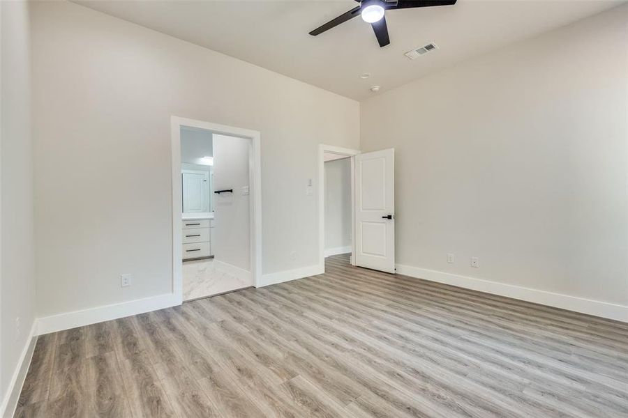 Unfurnished bedroom with ceiling fan, ensuite bath, and light hardwood / wood-style floors