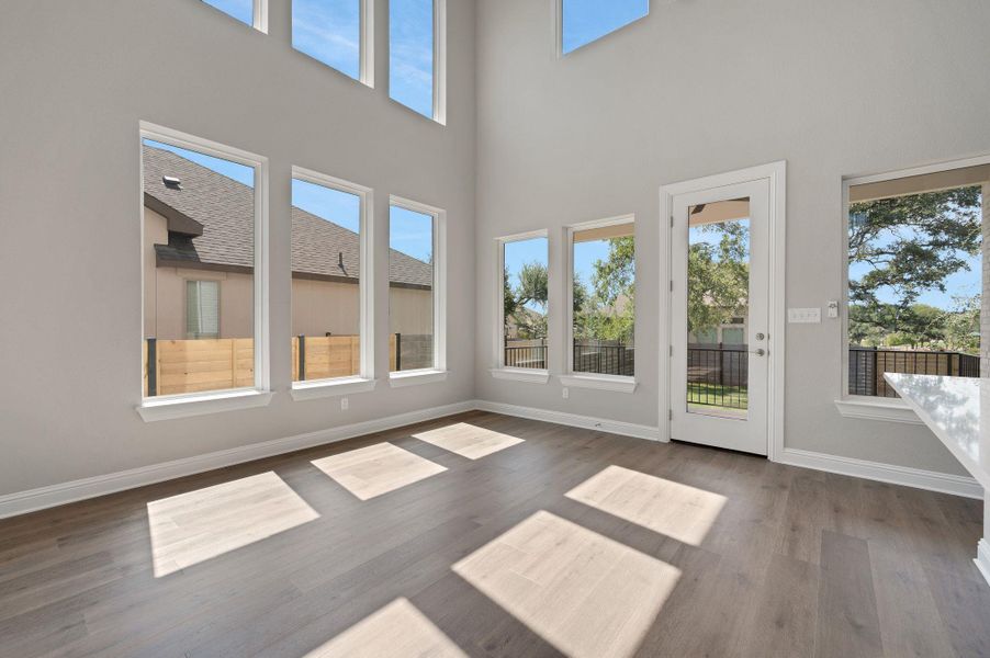 Unfurnished sunroom featuring wood finished floors and a towering ceiling