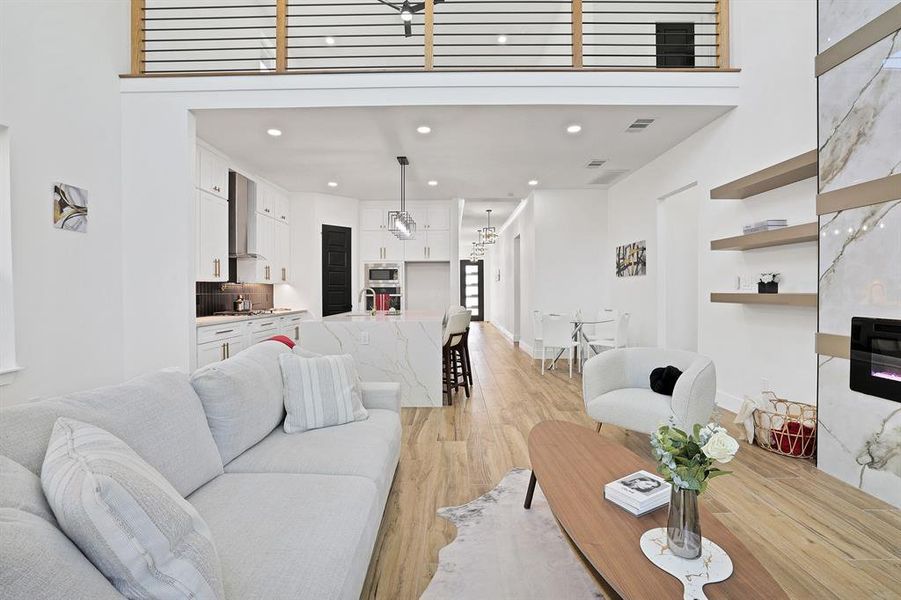 Living room featuring light hardwood / wood-style flooring, a towering ceiling, and sink