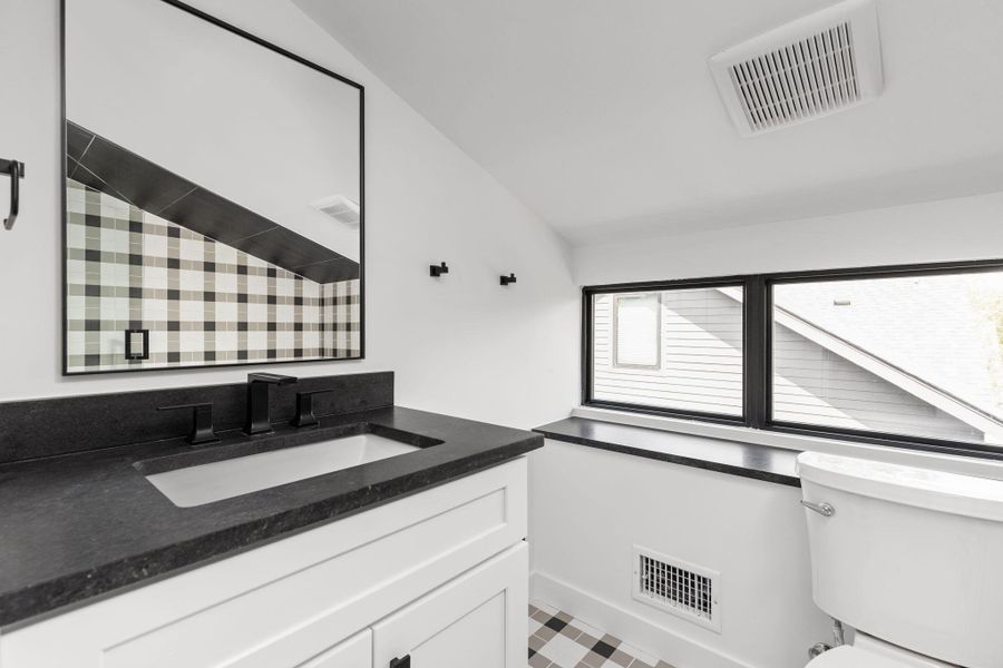 Bathroom with vanity and lofted ceiling