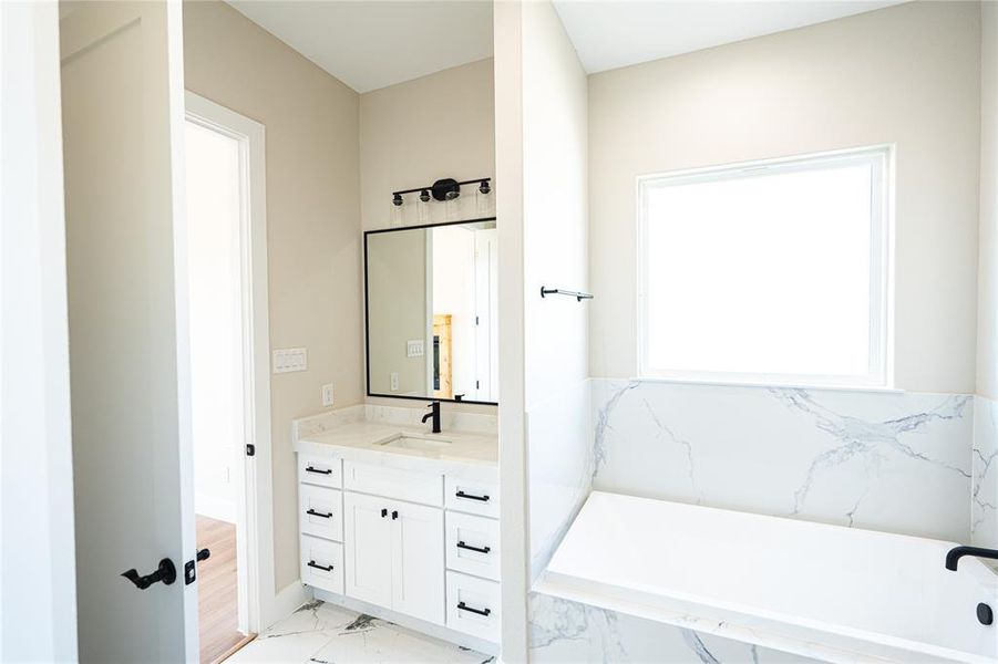 Full bathroom with vanity, a garden tub, and light marble finish flooring