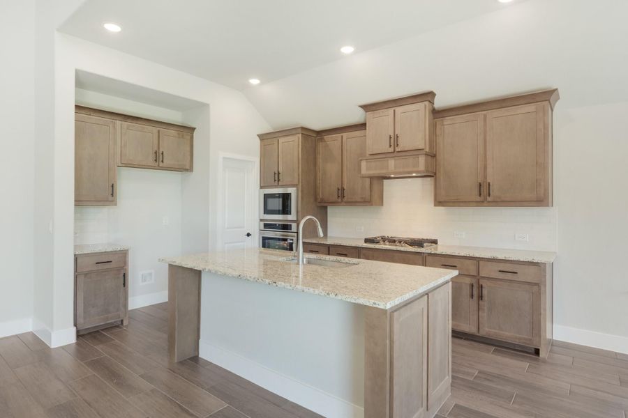 Kitchen with large center island, granite countertops, tan wood cabinets, and stainless steel double oven Kitchen with large center island, granite countertops, tan wood cabinets, and stainless steel double oven